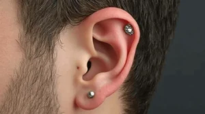 Close-up of a man's right ear with two silver stud piercings