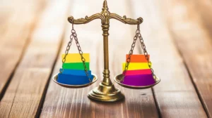 LGBT rainbow paper stacks balanced on golden justice scales on a wooden table